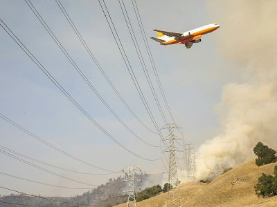 Un avion bombardier d'eau survole les flammes de l'incendie du "Kincade Fire", en Californie - Philip Pacheco [AFP]