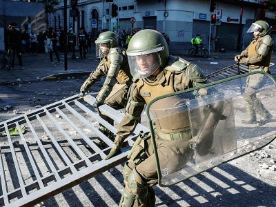 Des policiers anti-émeutes déblaient une barricade pendant des heurts avec des manifestants antigouvernementaux le 28 octobre à Santiago (Chili) - Pedro Ugarte [AFP]