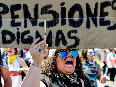Une femme tient une pancarte réclamant "des retraites dignes" devant le palais présidentiel de La Moneda à Santiago le 30 octobre 2019 - Martin BERNETTI [AFP]