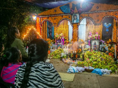 Des femmes prient devant des autels couverts d'offrandes à l'occasion du jour des morts, le 31 octobre 2019 à Santa Fe de la Laguna, au Mexique - ENRIQUE CASTRO [AFP]