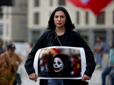 Cynthia Aboujaoude, une manifestante libanaise, tient une photo d'elle grimée en Joker, à Beyrouth le 23 octobre 2019. - Patrick BAZ [AFP]