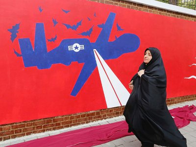Une Iranienne passe devant une fresque murale sur l'enceinte de l'ancienne ambassade américaine à Téhéran, le 2 novembre 2019 - ATTA KENARE [AFP]