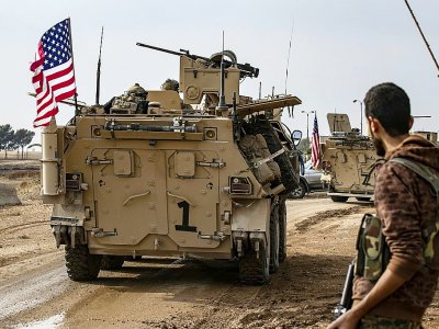 Un combattant des Forces démocratiques syriennes, dominées par les Kurdes, regarde un convoi américain passer près de la ville de Qamichli, dans le nord-est de la Syrie, le 2 novembre 2019 - Delil SOULEIMAN [AFP]