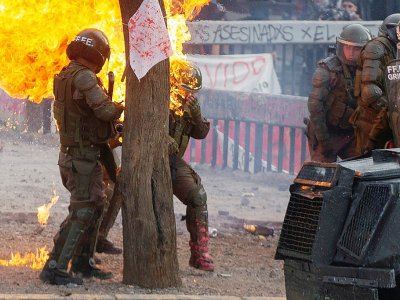 Des policiers anti-émeutes atteints par un cocktail molotov lors d'une manifestation contre le gouvernement à Santiago du Chili le 4 novembre 2019 - Claudio REYES [AFP]