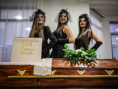 Des mannequins habillées en veuves posent le 2 novembre 2019 devant un gâteau en forme de cercueil à la fête des croque-morts de Pozarevac, en Serbie - Andrej ISAKOVIC [AFP]