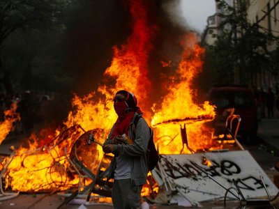 Un manifestant passe devant une barricade enflammée, le 8 novembre 2019 à Santiago - CLAUDIO REYES [AFP]
