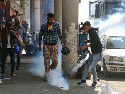 Des manifestants irakiens tentent d'éteindre des gaz lacrymogènes tirés par les forces de sécurité à Bagdad le 9 novembre 2019 - SABAH ARAR [AFP]