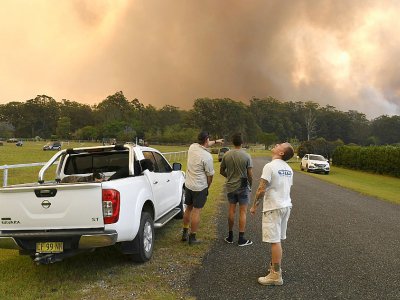 Des habitants observent un incendie près de la localité australienne de Nana Glen, à environ 600 km au nord de Sydney, le 12 novembre 2019 - WILLIAM WEST [AFP]