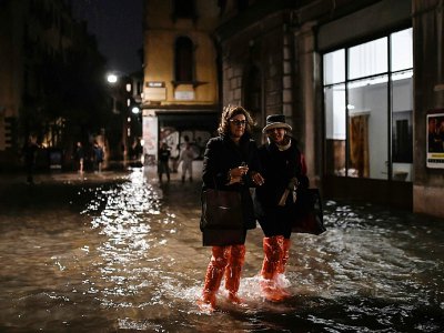 Des badauds, chaussés de sacs en plastique, à Venise le 12 novembre 2019 - Marco Bertorello [AFP]