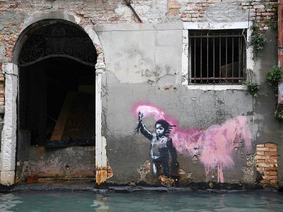 Une oeuvre de l'artiste de rue Banksy, représentant un enfant migrant avec un gilet de sauvetage et une fusée de détresse, sur un mur d'une rue inondée, à Venise le 13 novembre 2019 - Marco Bertorello [AFP]