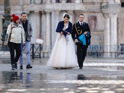 Un couple tout juste marié traverse une place inondée, à Venise le 14 novembre 2019 - Filippo MONTEFORTE [AFP]