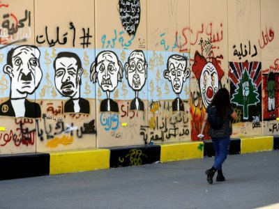 Une femme passe devant un mur de graffitis à Beyrouth le 6 novembre 2019 - JOSEPH EID [AFP]