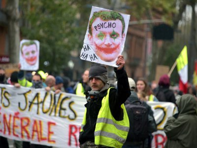 A Toulouse, un "gilet jaune" brandit un portrait d'Emmanuel Macron maquillé en "joker", le 16 novembre 2019, pour le premieer anniversaire du mouvement de contestation sociale - PASCAL PAVANI [AFP]