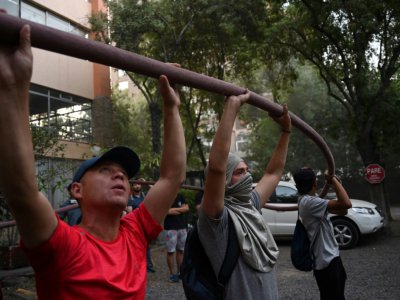 Des manifestants aident les pompiers à éteindre un incendie lors d'affrontements avec les forces de l'ordre, le 16 novembre 2019 à Santiago du Chili - Johan ORDONEZ [AFP/Archives]
