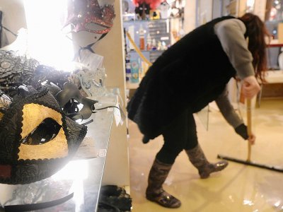 Une femme nettoie une boutique de souvenirs à Venise, affectée par un phénomène de montée des eaux ("acqua alta") historique, le 17 novembre 2019 - Filippo MONTEFORTE [AFP]