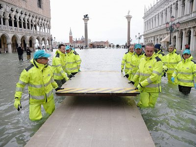 Des ouvriers installent un pont provisoire sur la place Saint-Marc de Venise, envahie par les eaux, le 17 novembre 2019 - Filippo MONTEFORTE [AFP]