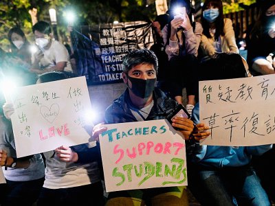 Des manifestants tiennent des pancartes et des téléphones portables alors qu'ils prient pour les étudiants barricadés sur le campus de l'université polytechnique de Hong Kong, le 19 novembre 2019 - YE AUNG THU [AFP]