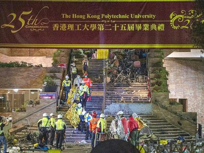 Des manifestants enveloppés dans des couvertures de survie, aidés par des équipes de secours, quittent le campus de l'université polytechnique de Hong Kong, le 19 novembre 2019 - NICOLAS ASFOURI [AFP]