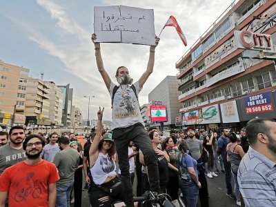 Un jeune libanais brandit une banderole sur laquelle est écrit "Vous brûlez notre avenir", lors d'une manifestation contre le pouvoir à Zouk Mosbeh, au nord de Beyrouth, le 18 octobre 2019 - JOSEPH EID [AFP]