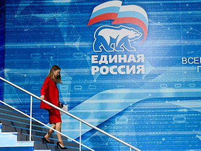 Une membre de Russie unie passe devant le logo du parti à Moscou le 8 décembre 2018 - Kirill KUDRYAVTSEV [AFP]
