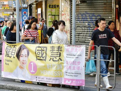 Des passants devant des affiches électorales dans le quartier de Wanchai à Hong Kong le 22 novembre 2019 - Nicolas ASFOURI [AFP]