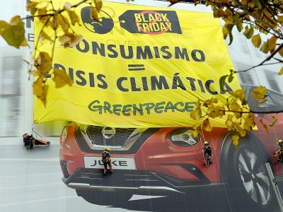 Des militants de Greenpeace ont déployé sur la façade d'un immeuble le 29 novembre 2019 à Madrid une énorme banderole : "Consumérisme=Crise climatique" - PIERRE-PHILIPPE MARCOU [AFP]