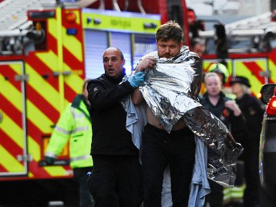 Un policier aide un homme blessé près du London Bridge, le 29 novembre 2019 à Londres - DANIEL SORABJI [AFP]