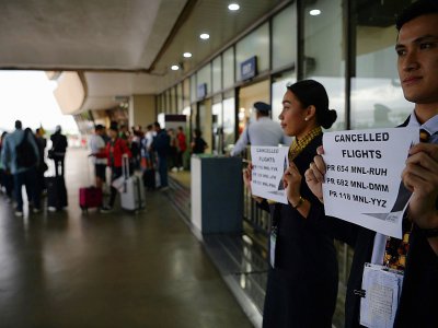 Du personnel de compagnies aériennes annoncent l'annulation de vols à l'aéroport international de Manille fermé en raison du typhon Kammuri, le 3 décembre 2019 - Ted ALJIBE [AFP]