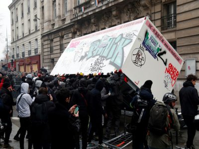 Des manifestants habillés tout en noir parviennent à renverser une remorque de chantier qui sera incendiée, à Paris le 5 décembre 2019 - Zakaria ABDELKAFI [AFP]