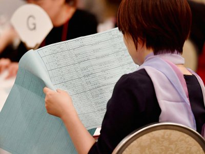 Une jeune femm consulte la liste des participants à une réception dans le cadre de rencontres à visées matrimoniales, à Tokyo, le 3 novembre 2019. - Toshifumi KITAMURA [AFP]