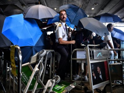 Un employé d'une compagnie aérienne tente de se frayer un chemin au milieu des manifestants à l'aéroport international de Hong Kong le 1er septembre 2019. - LILLIAN SUWANRUMPHA [AFP]