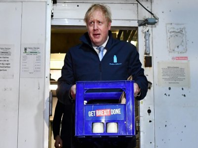 Le Premier ministre Boris Johnson porte un pack de bouteilles de lait  à Guiseley, dans le cadre de sa campagne électorale le 11 décembre 2019 - Ben STANSALL [POOL/AFP]