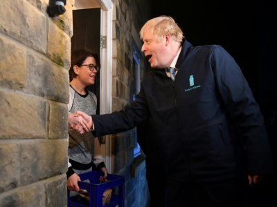 Boris Johnson apporte une bouteille de lait à Debbie Monaghan à Guiseley, le 11 décembre 2019 dans le cadre de sa campagne électorale - Ben STANSALL [POOL/AFP]