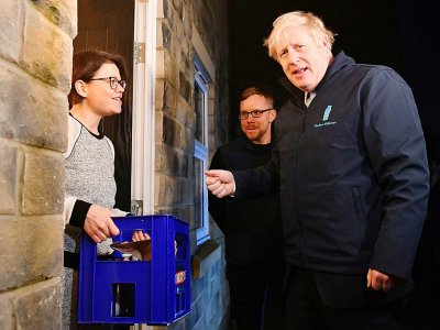Boris Johnson, en campagne pour les élections de jeudi, livre du lait à une famille de  Guiseley, dans le nord de l'Angleterre, le 11 décembre 2019 - Ben STANSALL [POOL/AFP]