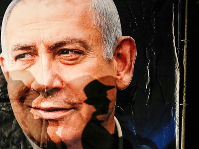 L'ombre d'un passant se projette sur un portrait du Premier ministre israélien Benjamin Netanyahu, à Jérusalem, le 11 décembre 2019 - AHMAD GHARABLI [AFP]