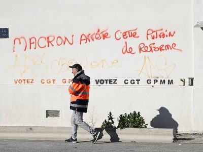 Un docker passe devant un slogan contre la réforme des retraites, lords du blocage du port autonome de Marseille, le 12 décembre 2019 - Christophe SIMON [AFP]