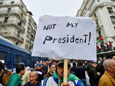 Un manifestant à Alger brandit une pancarte sur laquelle on peut lire "Pas mon président", le 13 décembre 2019 - RYAD KRAMDI [AFP]