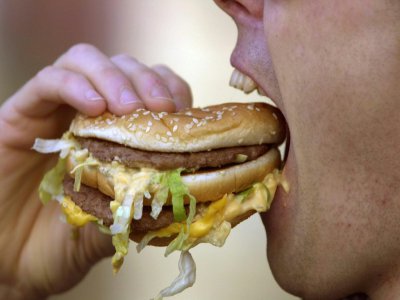 Un homme mange un hamburger, le 10 mars 2001 dans une rue de Caen - MYCHELE DANIAU [AFP/Archives]