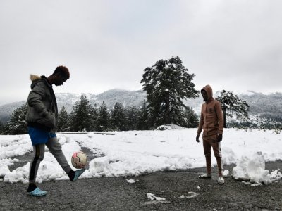 Deux migrants jouent au foot près d'un chalet transformé en camp de réfugiés près de Polineri, le 12 décembre 2019 en Grèce - Sakis MITROLIDIS [AFP]