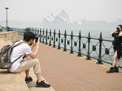 Des touristes portent des masques en raison des fumées toxiques liées aux incendies de forêts, le 10 décembre 2019 à Sydney, en Australie - PETER PARKS [AFP/Archives]