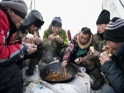 Des travailleurs déjeunent sur la rivière Songhua, le 12 décembre 2019 à Harbin, en Chine - NOEL CELIS [AFP]