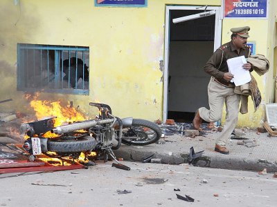 Un policier indien s'enfuit, tenant des documents, hors d'un commissariat attaqué par des manifestants contre la nouvelle loi sur la citoyenneté, à Lucknow le 19 décembre 2019 - STR [AFP]