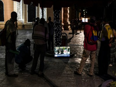 Des passants regardent la télévision dans la rue, place Bolivar, le 13 décembre 2019 à Caracas, au Venezuela - Yuri Cortez [AFP]