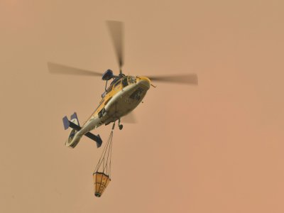 Un hélicoptère va larguer une charge d'eau sur un feu de forêt à Bargo, le 21 décembre 2019 en Australie - PETER PARKS [AFP]