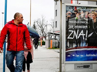 Un Croate regarde une affiche de la présidente Kolinda Grabar-Kitarovic, candidate à sa propre réelection, le 21 décembre 2019 à Zagreb - Denis LOVROVIC [AFP]