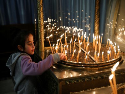 Un enfant allume des bougies à la basilique de la Nativité à Bethléem, en Cisjordanie occupée, le 23 décembre 2019 - AHMAD GHARABLI [AFP]