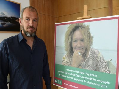 Sébastien Chabaud-Pétronin pose à côté d'une photo de sa mère, Sophie Pétronin, enlevée au Mali en décembre 2016, à Bordeaux, le 29 août 2018 - MEHDI FEDOUACH [AFP/Archives]