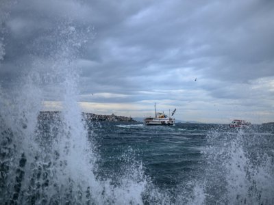 Un ferry passe sur le Bosphore alors que des vagues touchent la rive, le 23 décembre 2019 à Istanbul - BULENT KILIC [AFP]