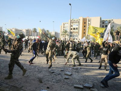 Des partisans des paramilitaires irakiens pro-iraniens du Hachd al-Chaabi jettent des pierres sur l'ambassade des Etats-Unis à Bagdad, le 31 décembre 2019 - AHMAD AL-RUBAYE [AFP]