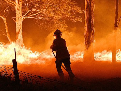 Un pompier lutte contre les flammes près de la ville de Nowra, en Nouvelle-Galles du Sud, le 31 décembre 2019 - SAEED KHAN [AFP]
